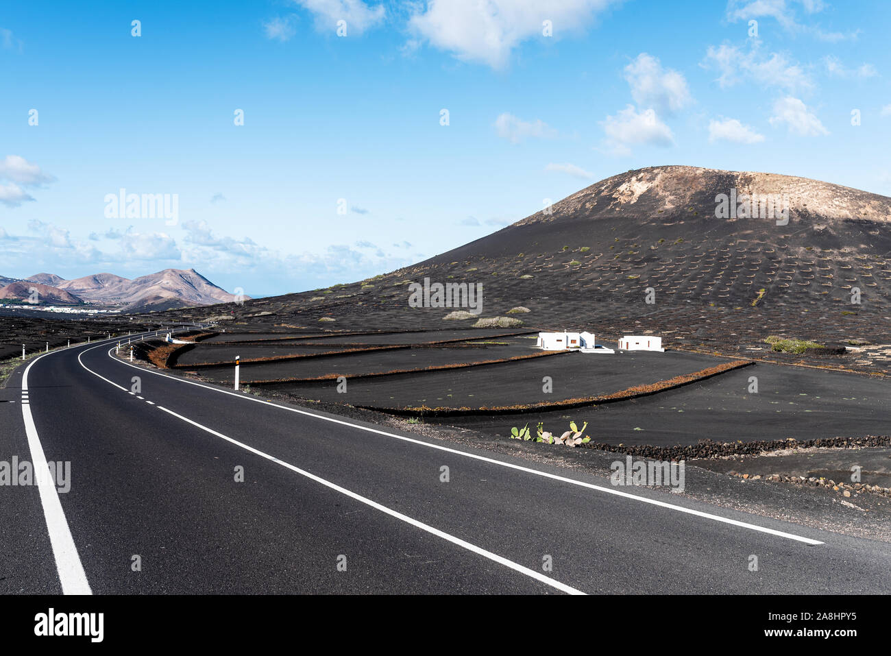 Strada asfaltata attraverso il paesaggio vulcanico a Lanzarote isole Canarie contro il cielo blu Foto Stock