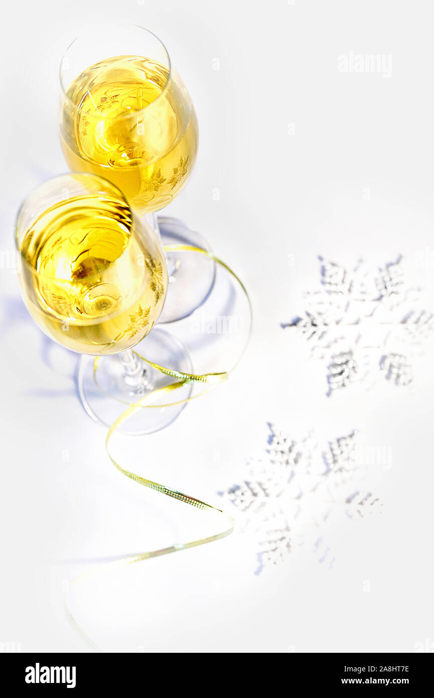 Due bicchieri di vino e fiocchi di neve su uno sfondo bianco. Concetto di vacanza Foto Stock