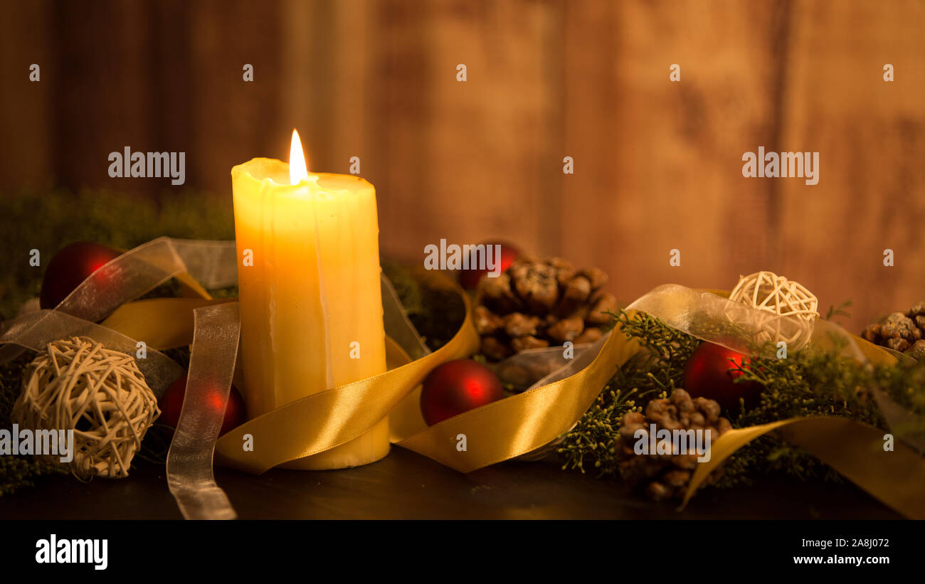 Il calore del concetto di Natale: close up di tre candele accese al buio su un tavolo in legno e con rami di pino, naturale pigne e oro e rosso Foto Stock