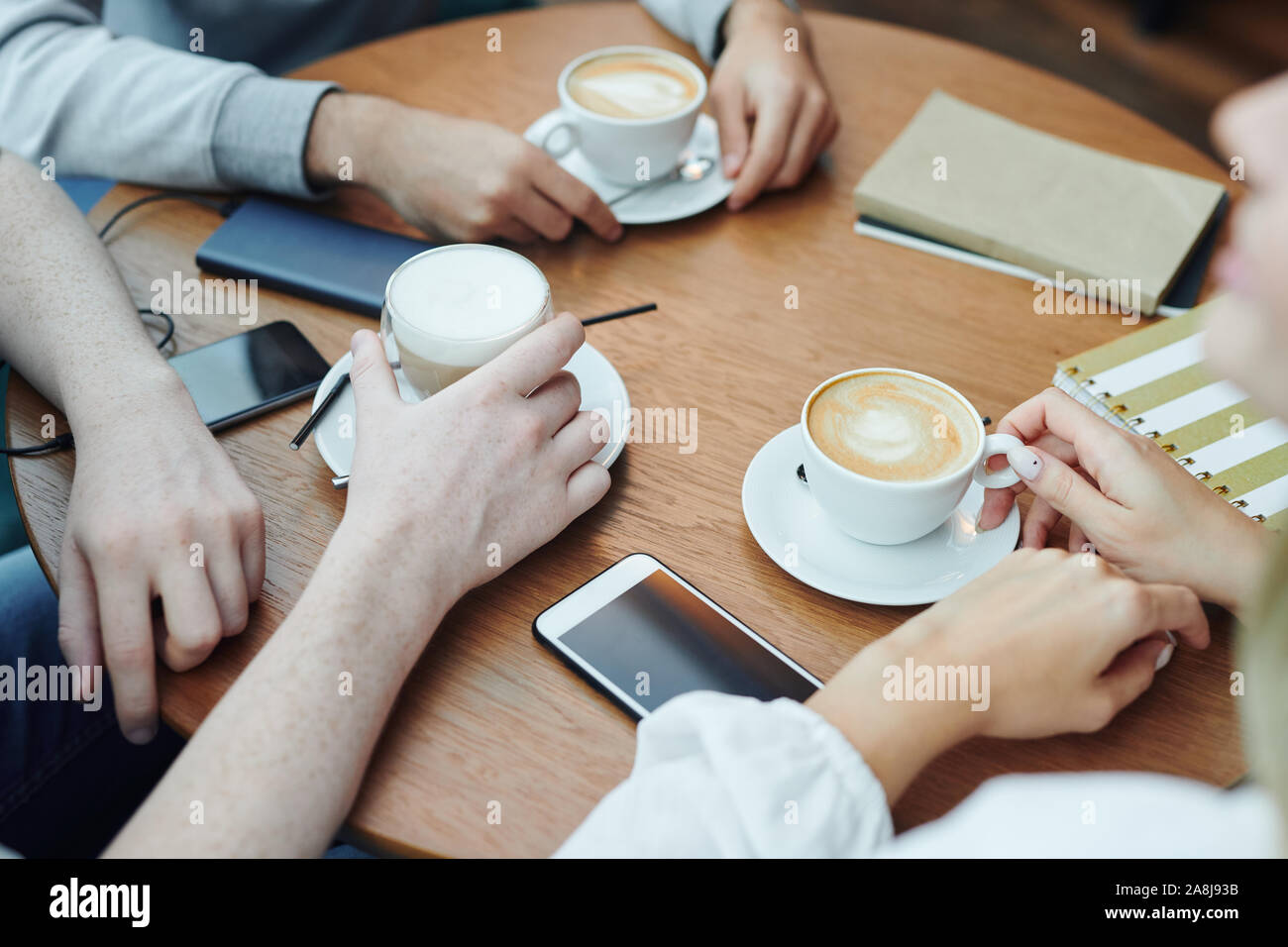 Le mani del collegio di amici con i gadget e bevande raccolte dalla tabella in cafe Foto Stock