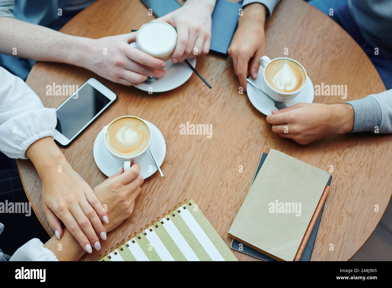 Mani di studenti universitari con i gadget e bevande raccolte dalla tabella in cafe Foto Stock