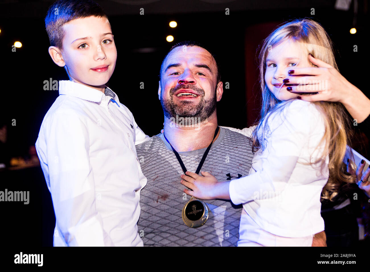 Padre Felice con insanguinato del naso e del labbro porta orgoglioso figlio e figlia sulle sue mani dopo aver vinto amature lotta nel collare bianco Boxing League a Kiev Foto Stock