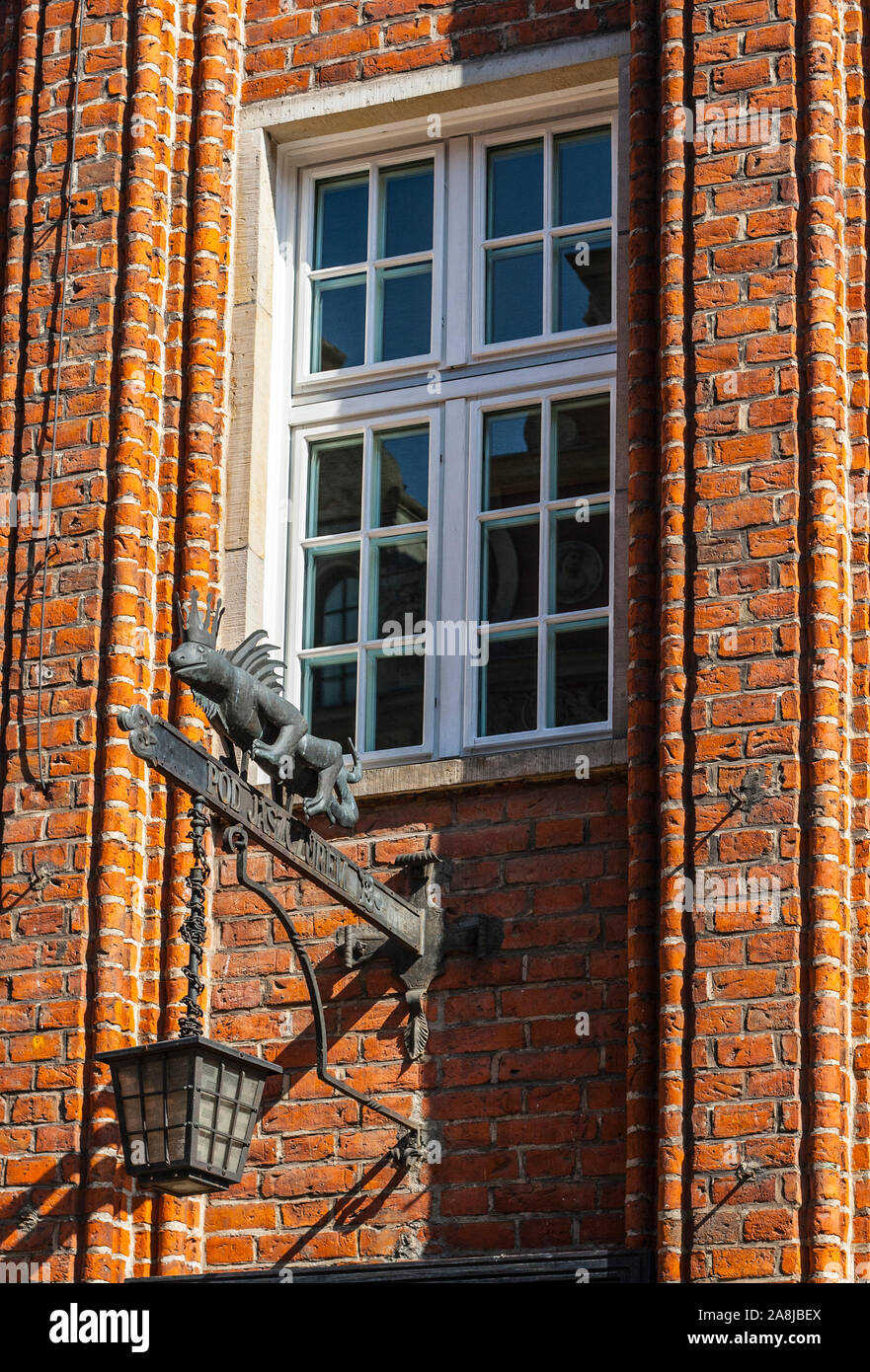 Ghisa segno commerciale e lanterna raffigurante la lucertola sotto il winfow bricky sulla parete del vecchio edificio in Gdansk, Polonia Foto Stock