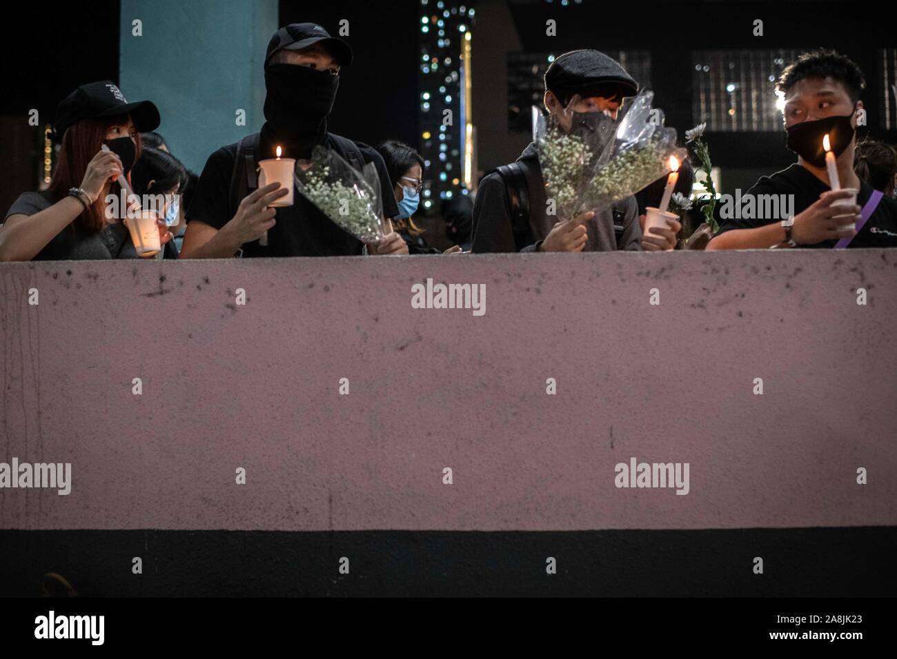 Placcato nero manifestanti con fiori e candele ad una cerimonia in memoria di Alex Chow durante le dimostrazioni.Hong Kong è in lutto per la morte di studente Chow Tsz-lok, 22 anni studente universitario che morì per arresto cardiaco nella mattina di venerdì 8 novembre. Chow Tsz-lok è scesa da un parcheggio in mezzo a scontri caotici tra Hong Kong polizia e manifestanti, soffre di una grave lesione alla testa. Migliaia hanno preso le strade per segnare il suo passaggio a. Cena a lume di candela a veglie si sono svolte presso il parcheggio auto nel caso in cui l'incidente ha avuto luogo. Foto Stock