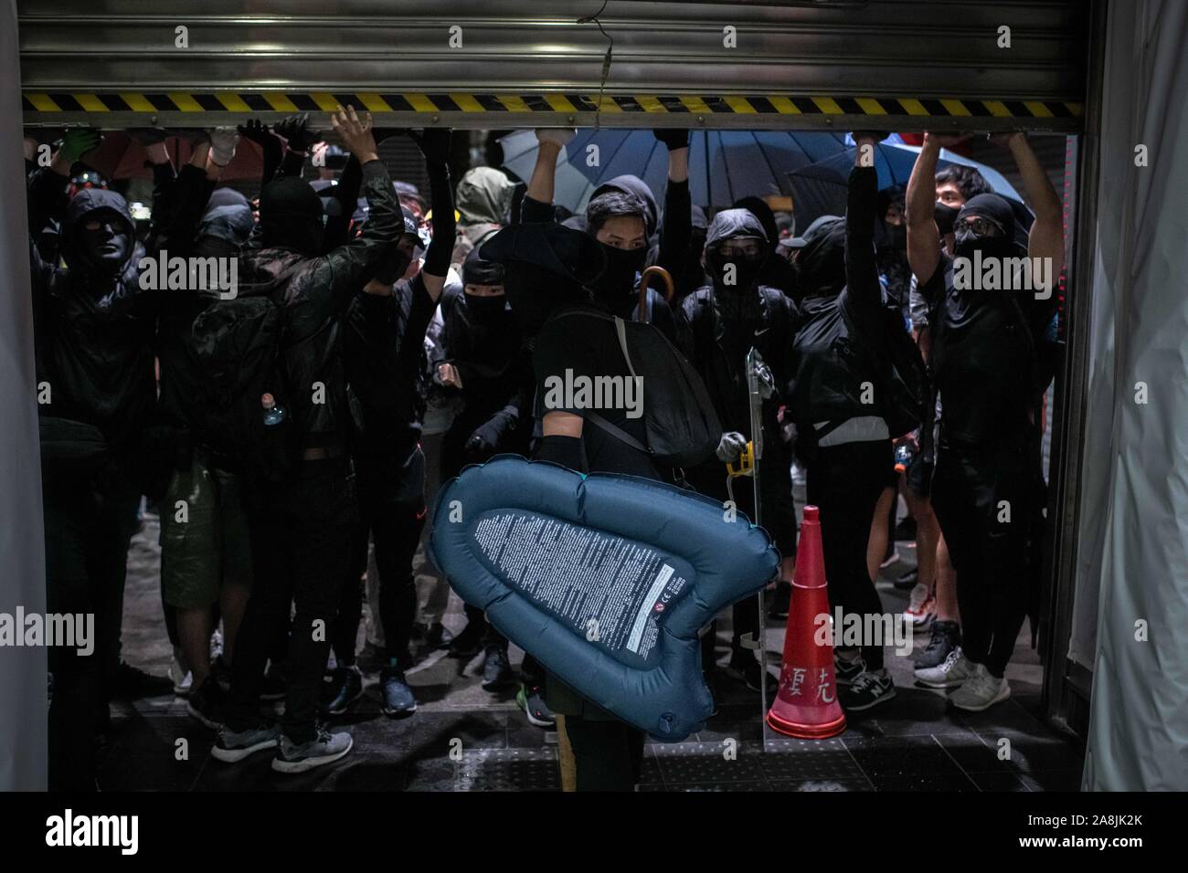 Un gruppo di nero manifestanti rivestito di tenere una porta automatica della stazione MTR durante le dimostrazioni.Hong Kong è in lutto per la morte di studente Chow Tsz-lok, 22 anni studente universitario che morì per arresto cardiaco nella mattina di venerdì 8 novembre. Chow Tsz-lok è scesa da un parcheggio in mezzo a scontri caotici tra Hong Kong polizia e manifestanti, soffre di una grave lesione alla testa. Migliaia hanno preso le strade per segnare il suo passaggio a. Cena a lume di candela a veglie si sono svolte presso il parcheggio auto nel caso in cui l'incidente ha avuto luogo. Foto Stock