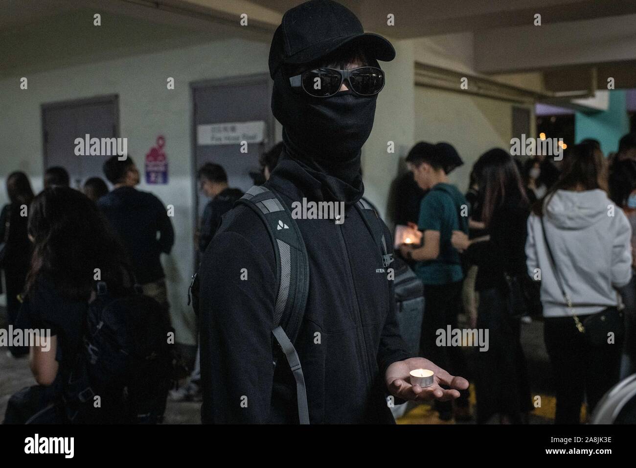 Placcato nero protester detiene una piccola candela ad una cerimonia in memoria di Alex Chow durante le dimostrazioni.Hong Kong è in lutto per la morte di studente Chow Tsz-lok, 22 anni studente universitario che morì per arresto cardiaco nella mattina di venerdì 8 novembre. Chow Tsz-lok è scesa da un parcheggio in mezzo a scontri caotici tra Hong Kong polizia e manifestanti, soffre di una grave lesione alla testa. Migliaia hanno preso le strade per segnare il suo passaggio a. Cena a lume di candela a veglie si sono svolte presso il parcheggio auto nel caso in cui l'incidente ha avuto luogo. Foto Stock