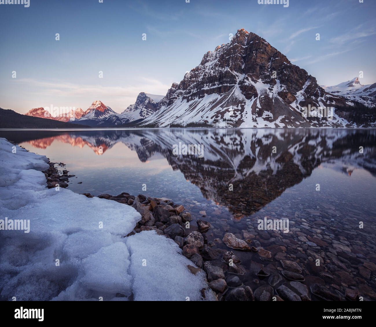 Calma inizio serata primaverile al Lago di prua con montagna Crowfoot riflessa sullo specchio come acque. Paesaggio di neve il parco nazionale di Banff, Montagne Rocciose Canadesi Foto Stock