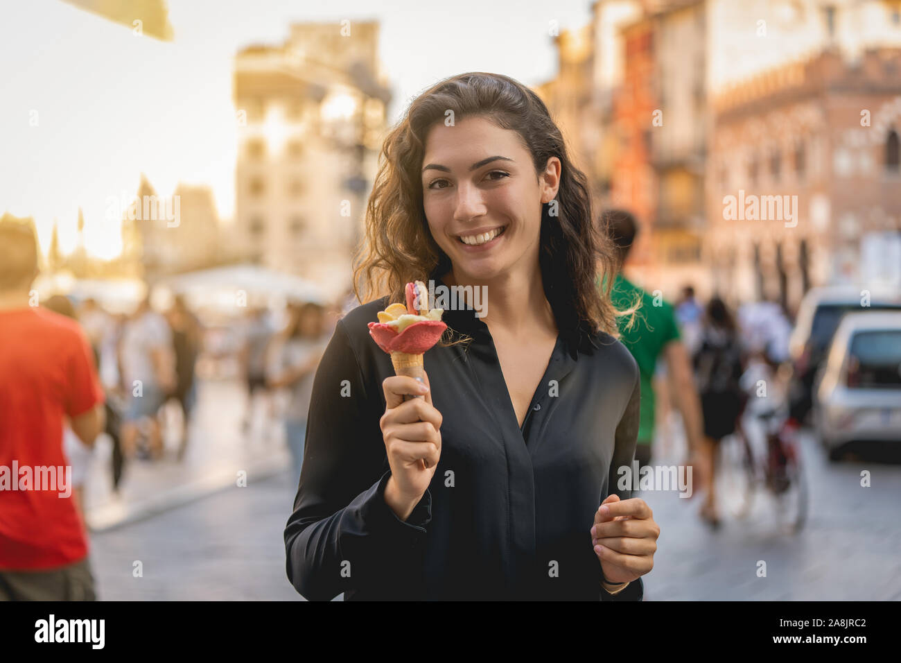 Sorridente ragazza turistiche a piedi con gelato per una città, vacanze Foto Stock