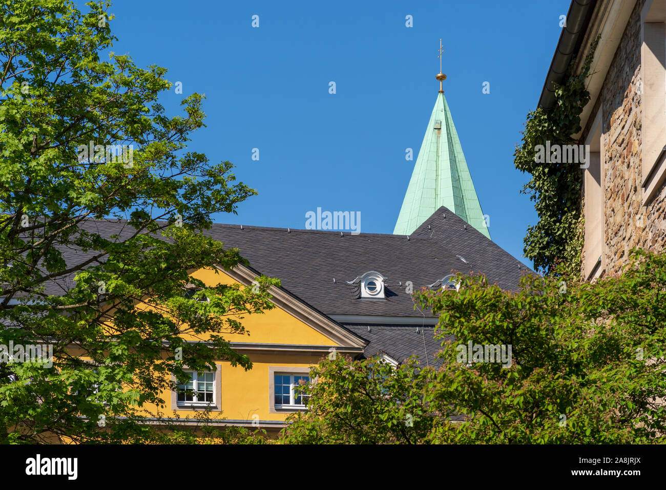 Tetto e timpano di un edificio della Folkwang Università delle Arti, la guglia della Basilica San Ludgerus, Essen-Werden, Germania Foto Stock