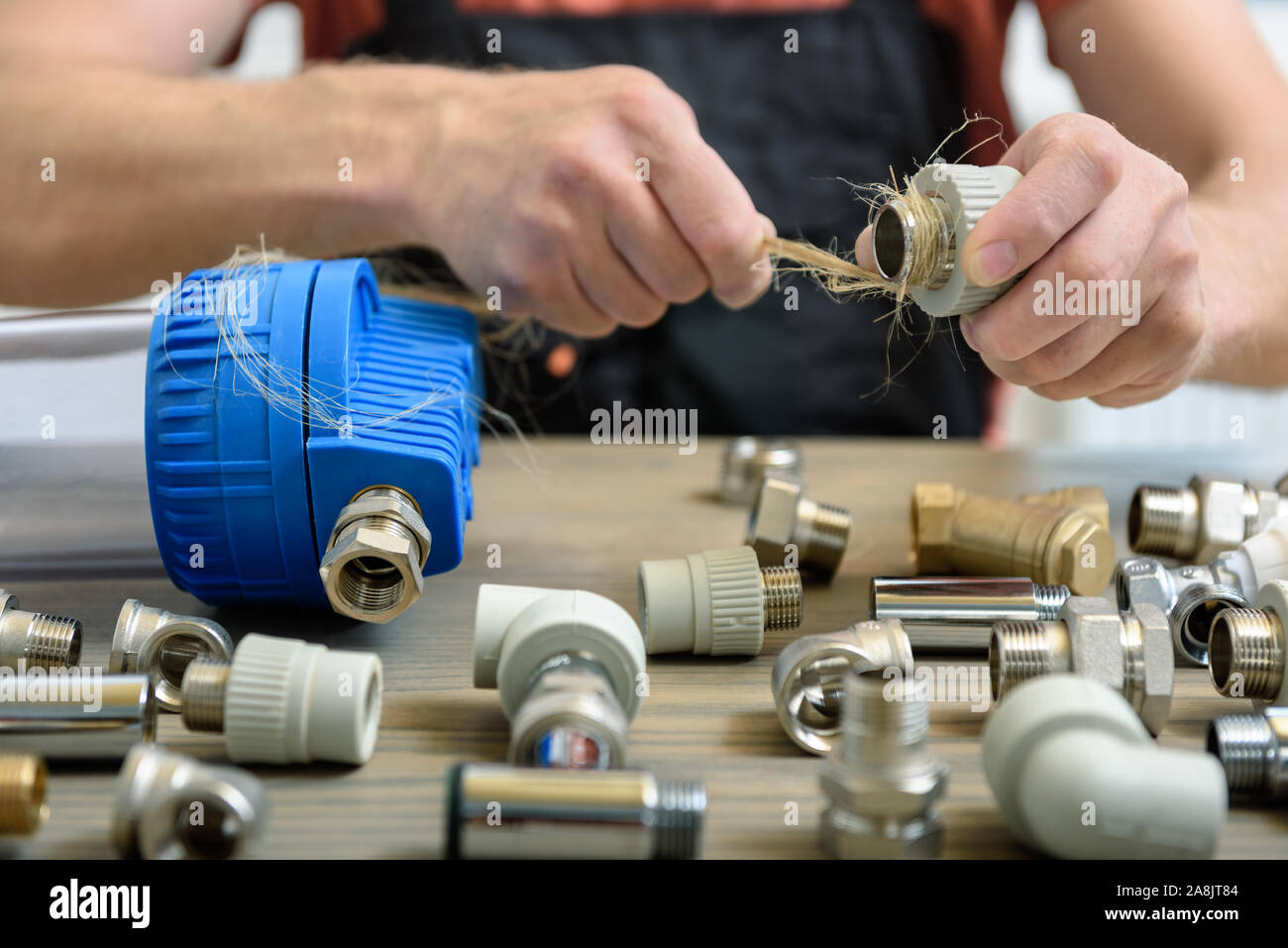 Il lavoratore è utilizzando un idraulico di fibre di canapa per la sigillatura di giunti dei tubi. Foto Stock