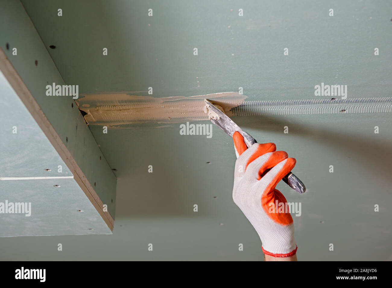 Un lavoratore è in fase di riempimento la plasterboards cuciture il gesso putty. Foto Stock