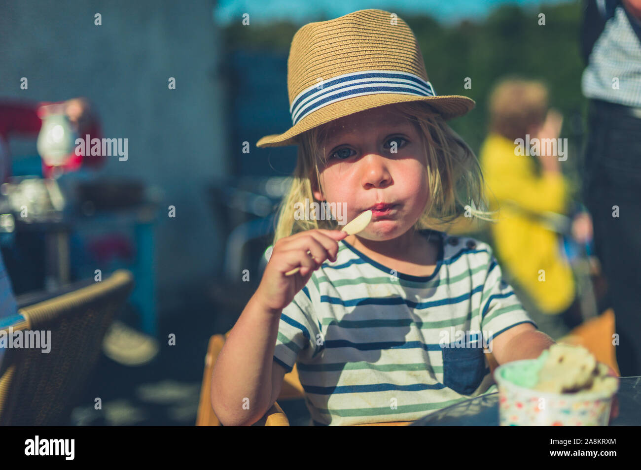 Un piccolo bambino è seduta al tavolo esterno e mangiare il gelato Foto Stock