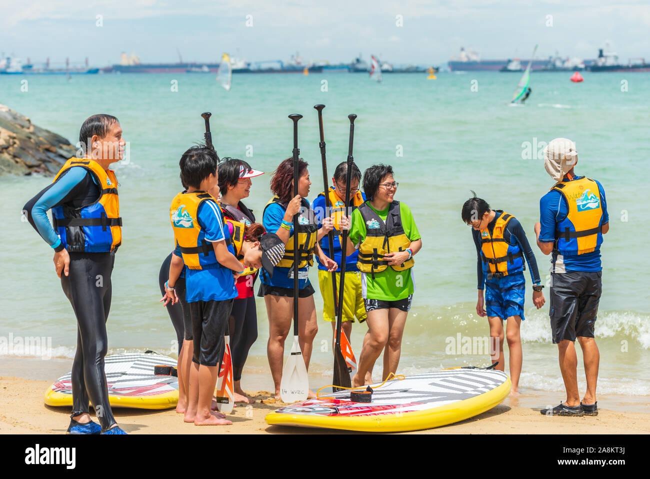 Un gruppo di uomini e donne windsurf sulla spiaggia di discussione Foto Stock
