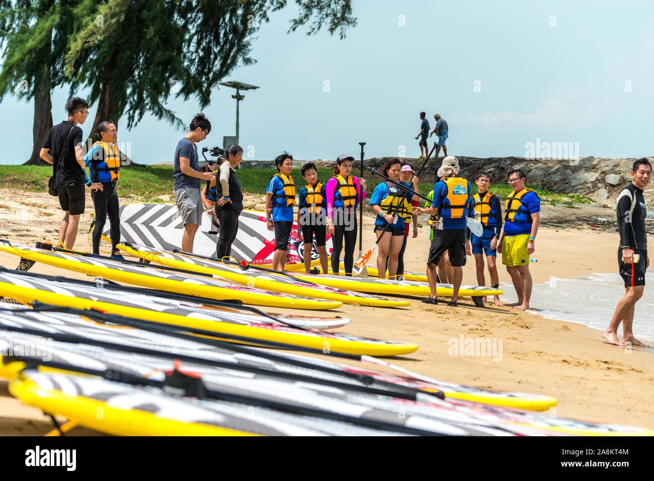 Un gruppo di uomini e donne windsurf sulla spiaggia di discussione Foto Stock