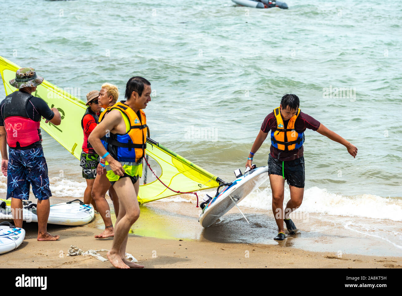 Gli uomini e le donne windsurfisti svolgere commissioni dopo la navigazione Foto Stock