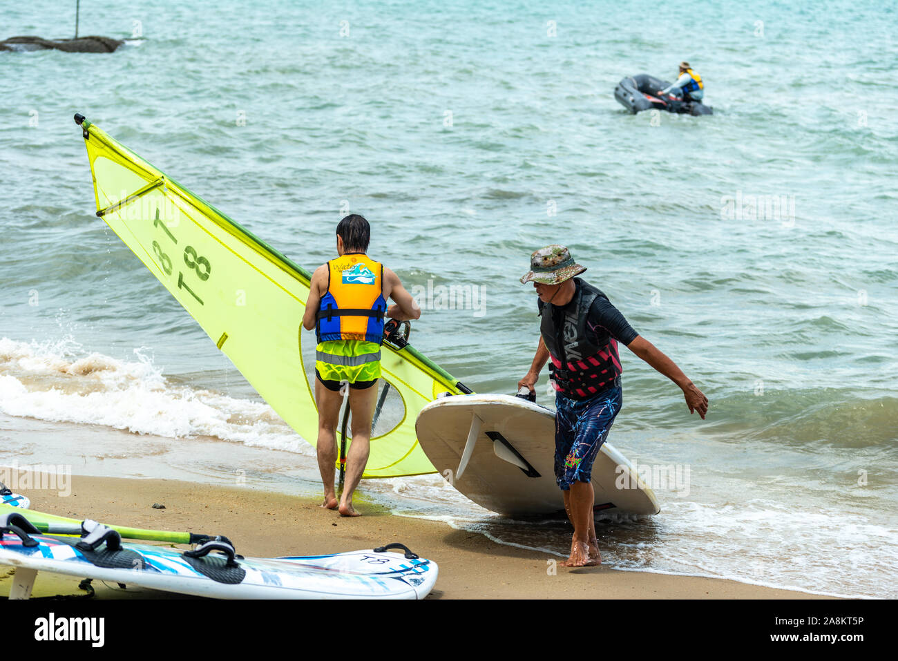 Gli uomini e le donne windsurfisti svolgere commissioni dopo la navigazione Foto Stock