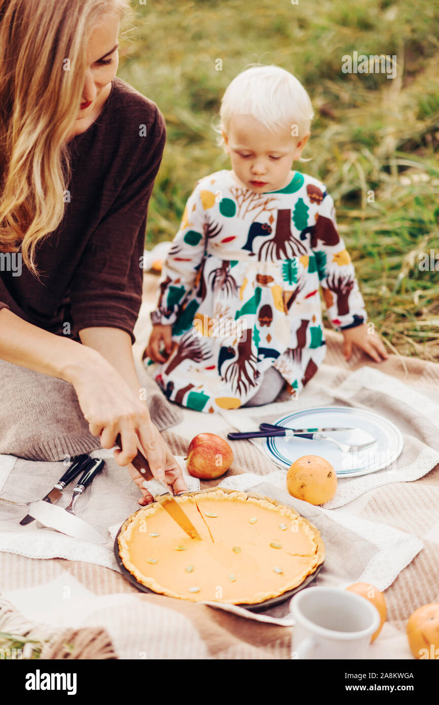 Mamma e figlia tagliare una torta su un picnic di autunno Foto Stock
