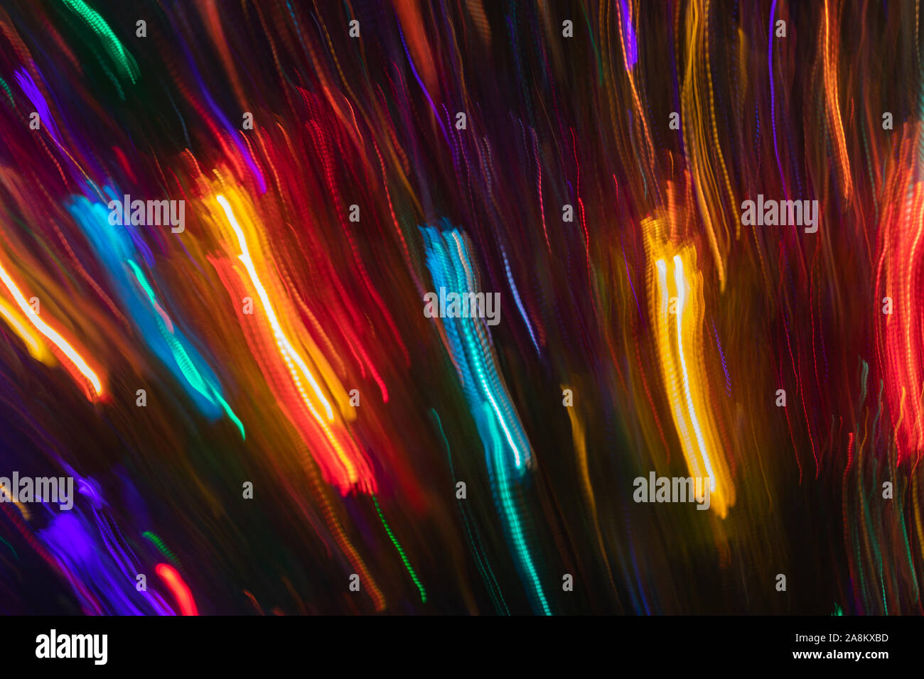 Sacco di variopinte sfocata e diagonale verticale strisce incandescente su sfondo scuro. Abstract sfondo al neon. Effetto fotografico con una lunga esposizione Foto Stock