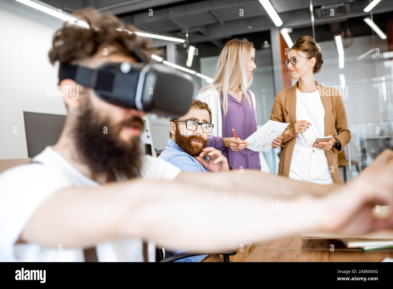 Giovani che lavorano in ufficio, creative uomo barbuto cercando un nuovo prodotto o un nuovo gioco di realtà virtuale gli occhiali di protezione Foto Stock