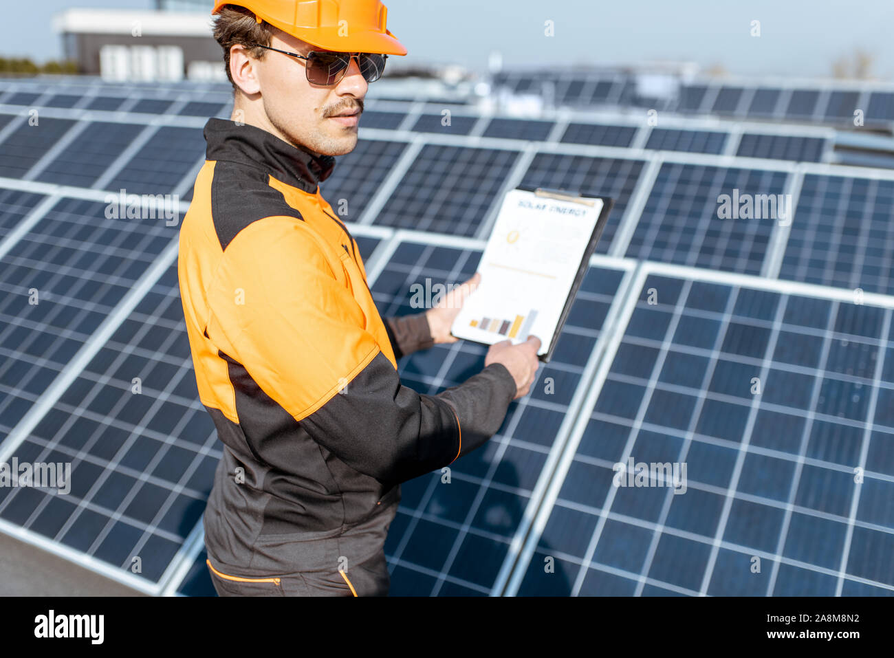 Workman tenendo un disegno con il grafico della produzione di energia elettrica su una centrale solare. Concetto di energia solare le prestazioni dell'impianto e la produzione Foto Stock