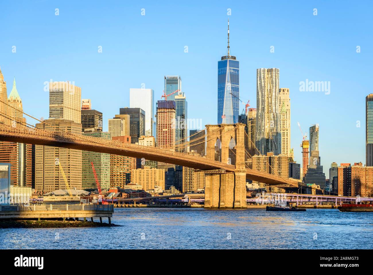 Ponte di Brooklyn nella luce del mattino, vista dal parco stradale e principale oltre l'East River per lo skyline di Manhattan con libertà torre o un mondo Foto Stock