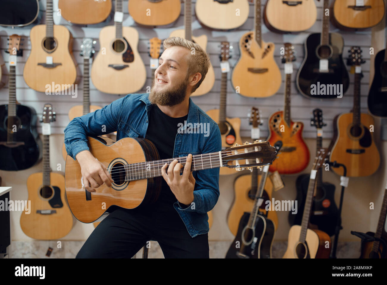 Giovane uomo gioca sulla chitarra acustica in music store Foto Stock