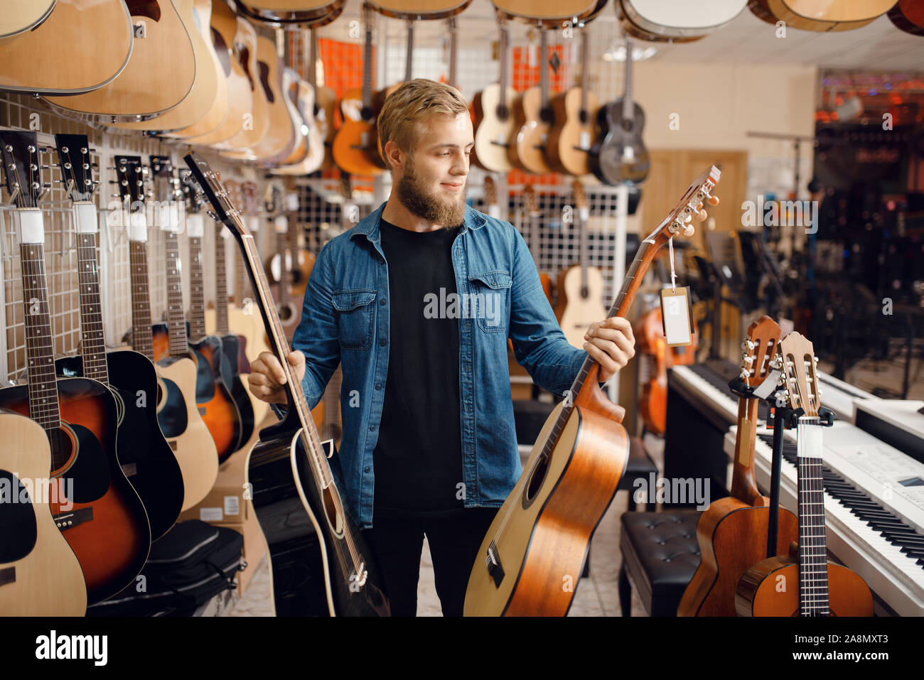 Giovane ragazzo scegliendo la chitarra acustica in music store Foto Stock
