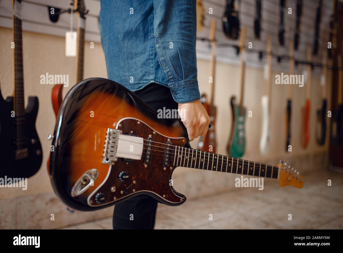 Giovane uomo con chitarra elettrica in music store Foto Stock