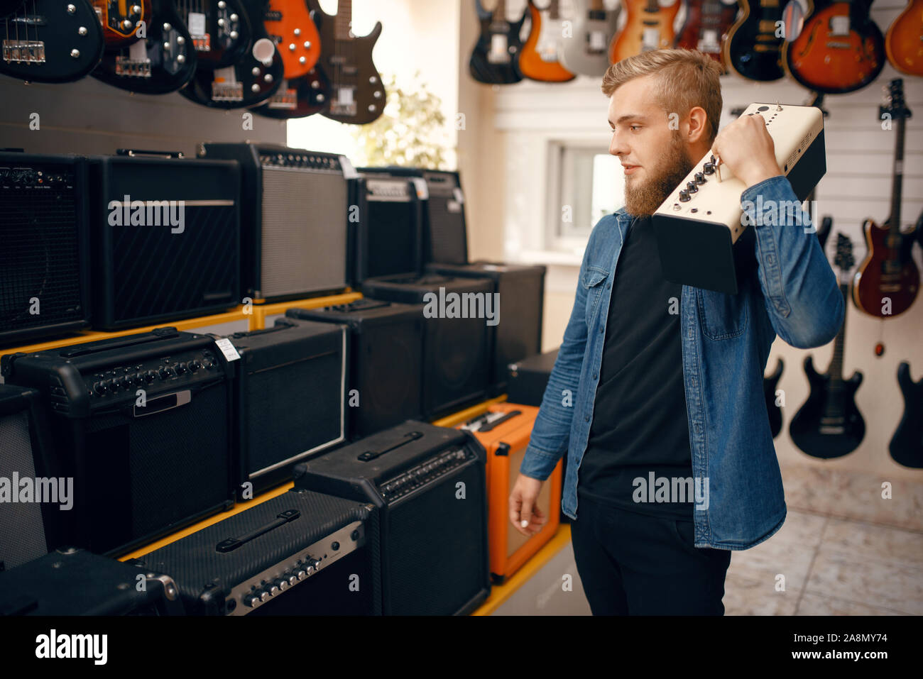 Giovane uomo scelta amplificatore combo in music store Foto Stock