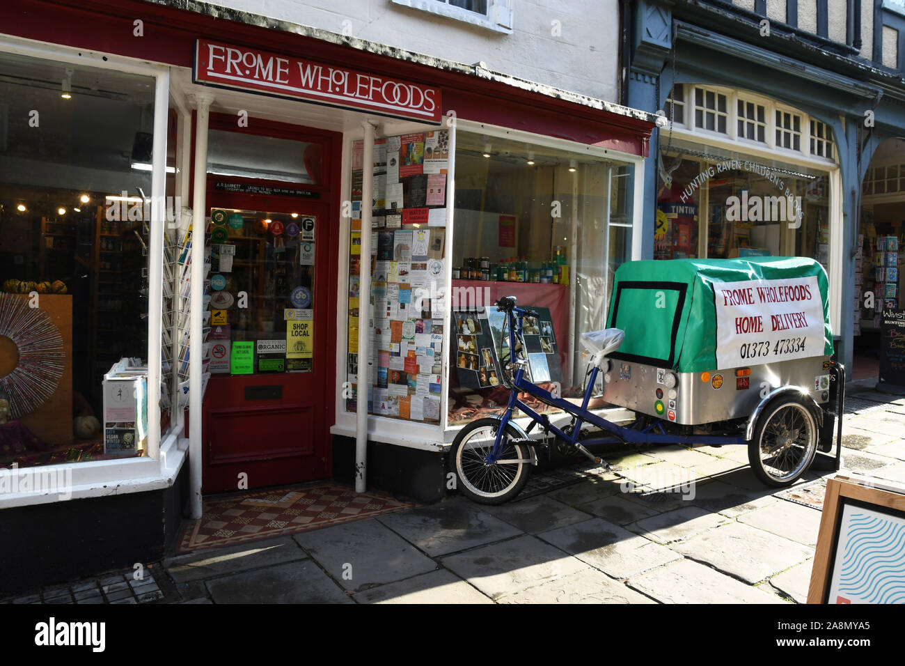 Eco Friendly veicolo di consegna al di fuori del negozio integrali in strada a buon mercato, Frome, Somerset. Piccoli commercianti indipendenti hanno negozi su entrambi i lati di una SAN Foto Stock