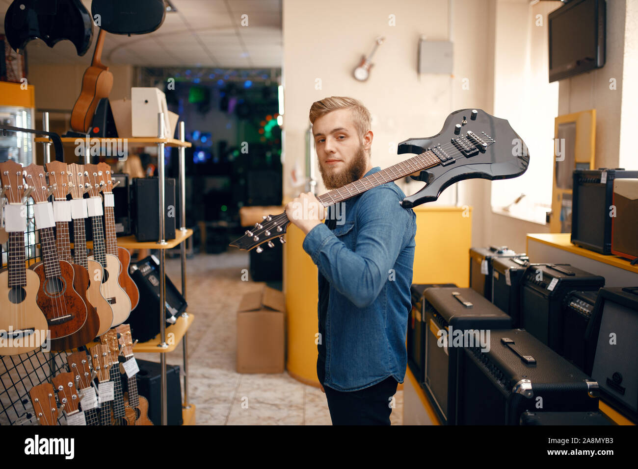 L'uomo pone con chitarra elettrica in music store Foto Stock