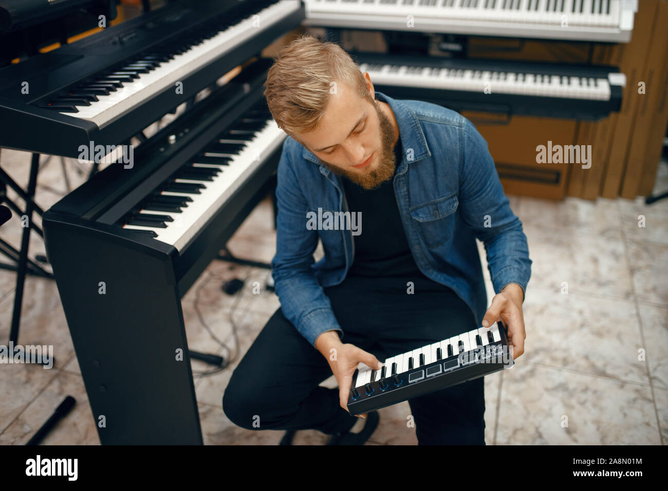 Giovane musicista sintetizzatore di acquisto in music store Foto Stock