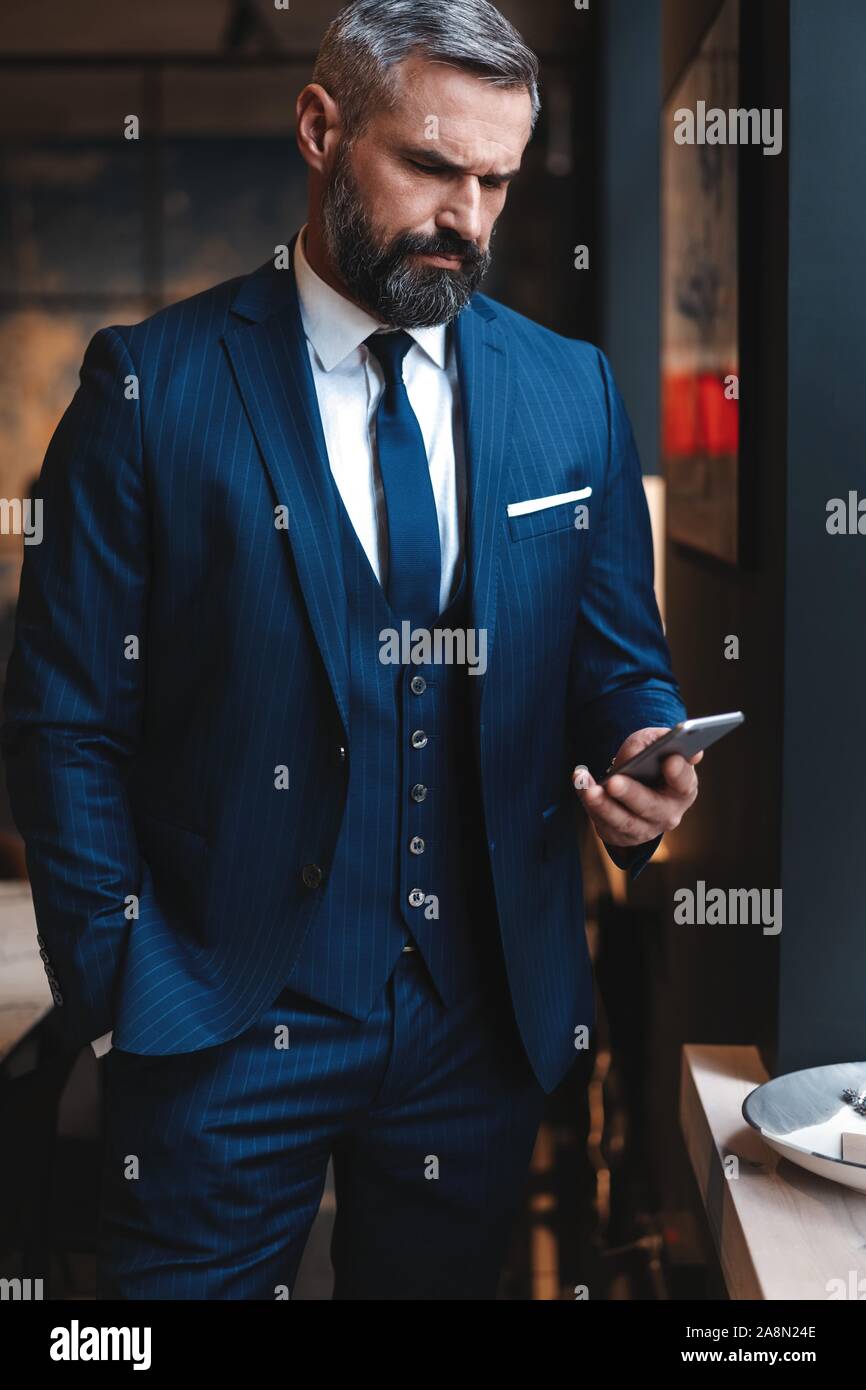 Formalmente vestiti maschio direttore esecutivo in vestiti alla moda  utilizzando il telefono cellulare Foto stock - Alamy