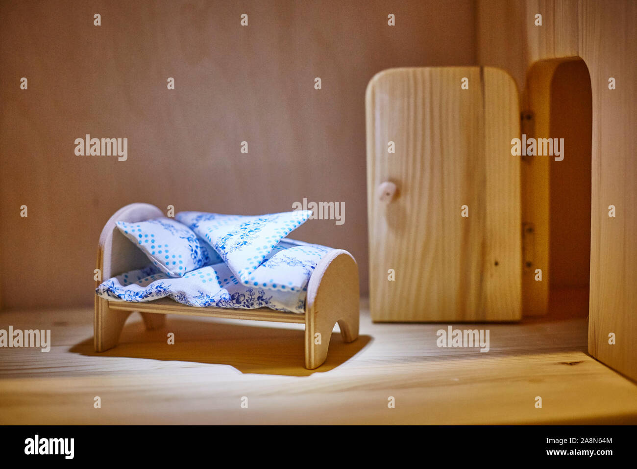 Legno compensato di bambola letto con coperte e cuscini in dollhouse. Miniatura. Foto Stock