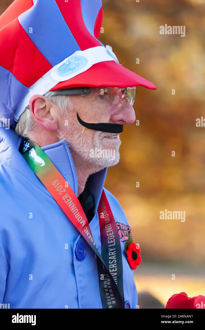 Glasgow, Scotland, Regno Unito. 10 Novembre, 2019. Un runner indossa un abito elegante costume all'inizio di MoRunning che è una serie di 1.5km, 5km e 10km di piste svolge in 24 sedi in tutto il Regno Unito & Irlanda nel mese di novembre in aiuto della Fondazione Movember che raccogliere fondi per la salute dell'uomo. Questo anno si festeggia il suo decimo anniversario e ha raccolto oltre 1 milione di sterline. Questi eventi sollevano i fondi per i principali problemi di salute di fronte a uomini che sono il cancro della prostata, cancro testicolare, salute mentale e il suicidio. Credito: Berretto Alamy/Live News Foto Stock