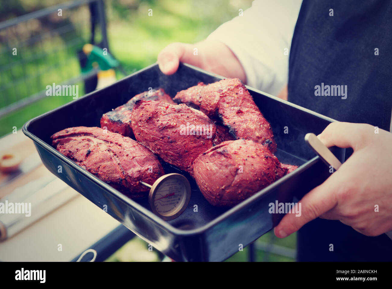 Lo Chef tenendo un vassoio con carne cotta, outdoor shot, tonica immagine Foto Stock