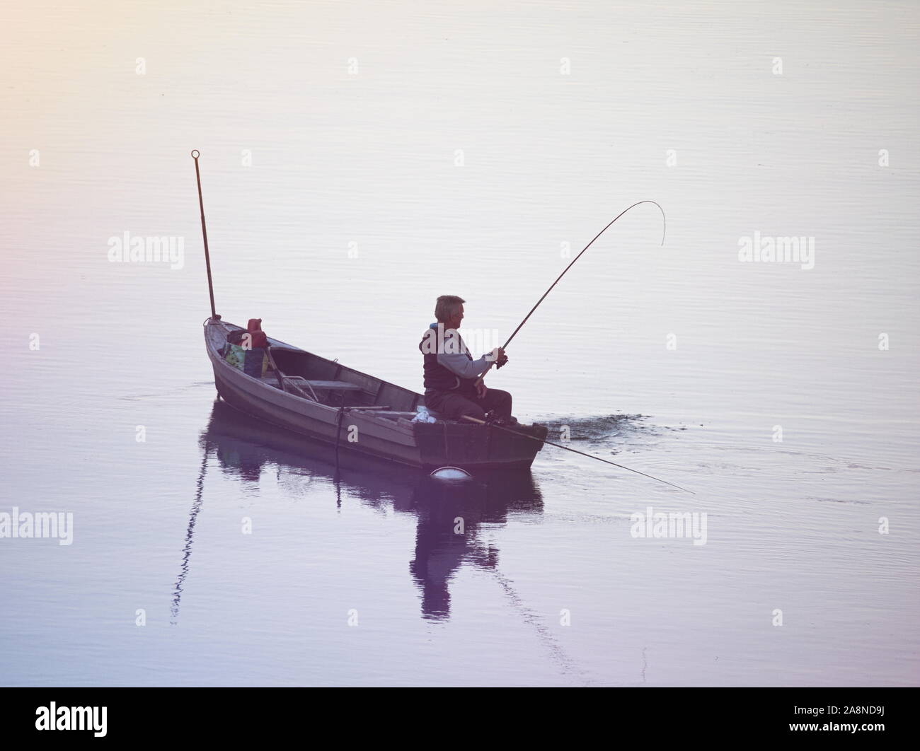 Fisherman seduti in barca piatta tirando la sua cattura Foto Stock