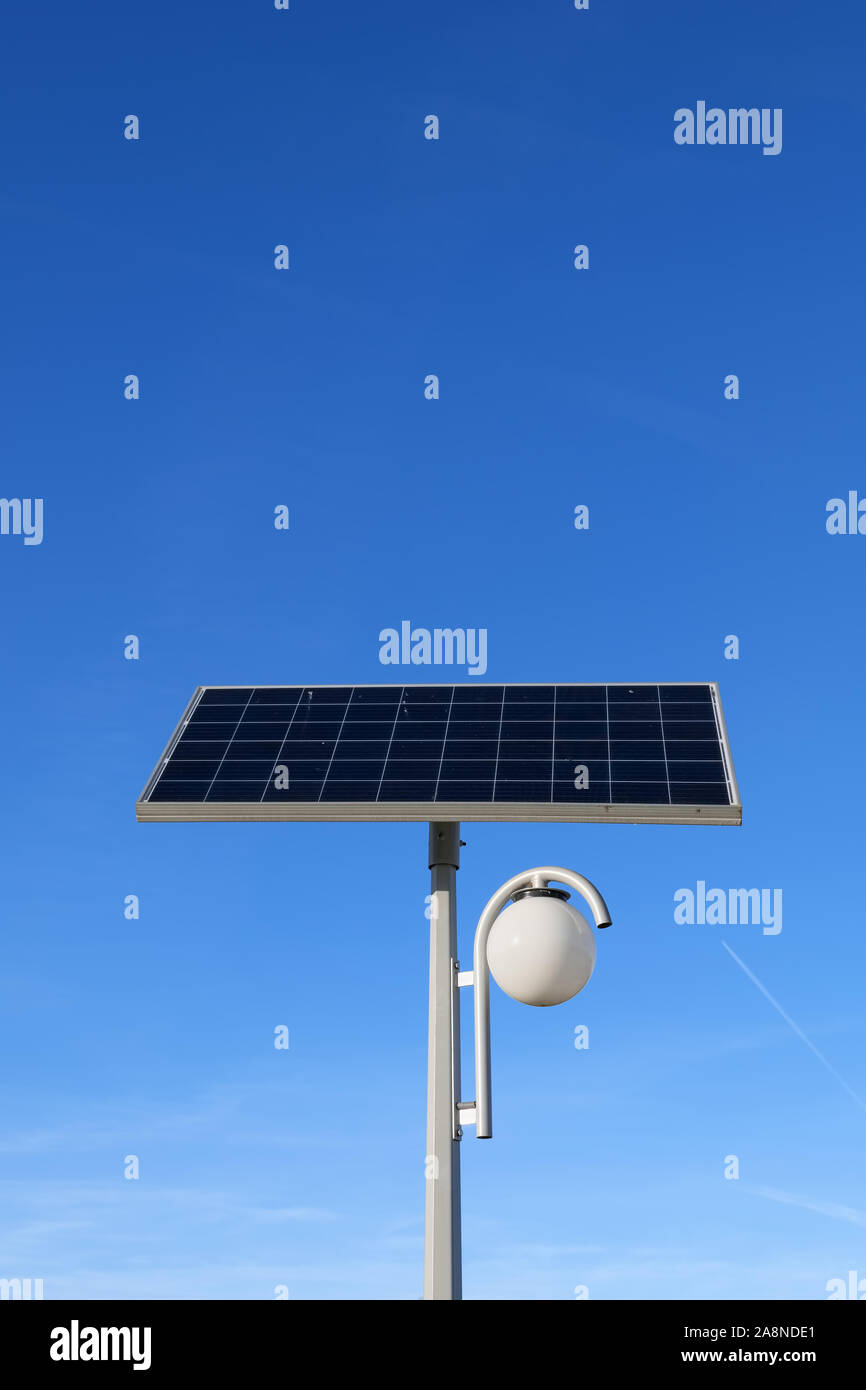 Lampada alimentata da pannello solare contro il cielo blu, lanterna con fonti di energia verde sorgente dal modulo fotovoltaico Foto Stock
