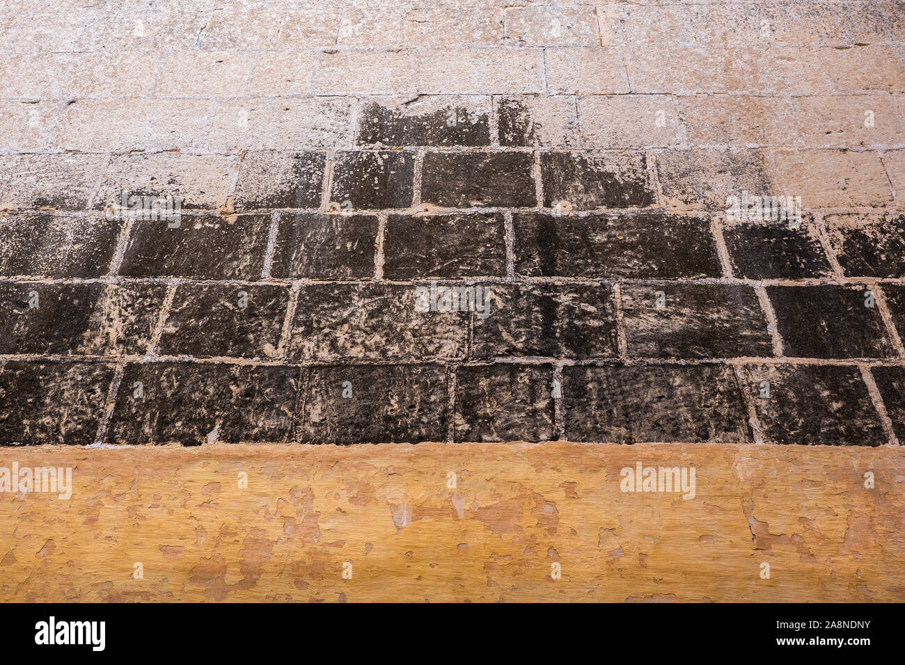 La pietra medievale sullo sfondo della parete o una texture dalla vecchia città di Mdina a Malta, in bianco e nero con orange a fondo. Foto Stock