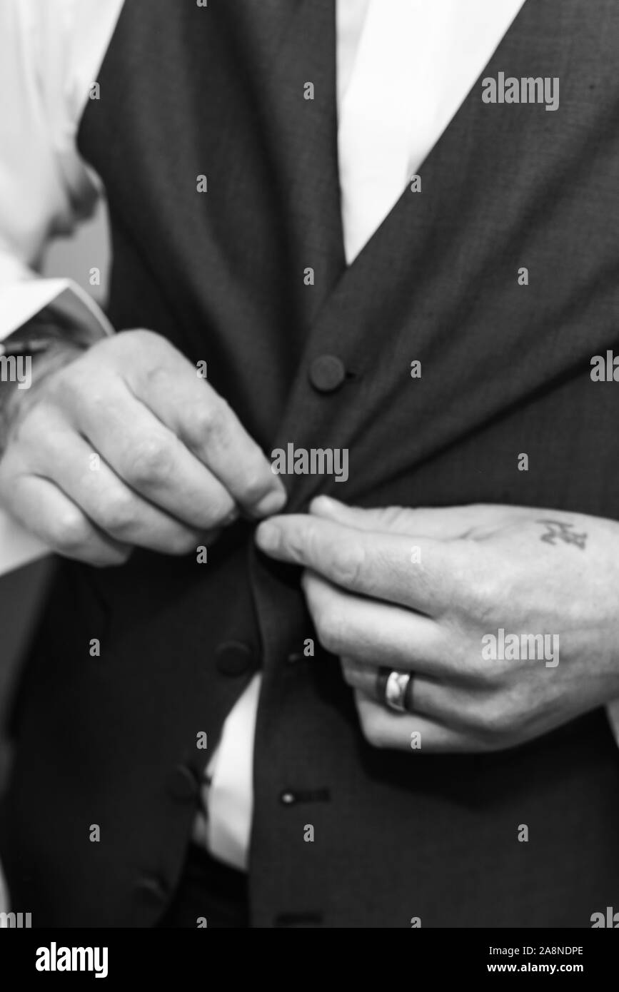 Un uomo sposo mettendo sul suo bretelle, i rigonfiamenti di loro alla sua pantaloni sul suo giorno di nozze. Abito formale, stilista e elegante, di fissaggio Foto Stock