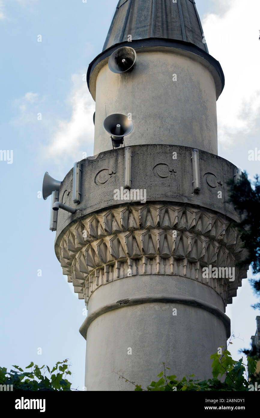Piccolo minareto della moschea Sahkulu presso Galata, Istanbul con triangolo turco pendenti, e una superficie in calcestruzzo con bandiera turca la mezzaluna e stella. Foto Stock