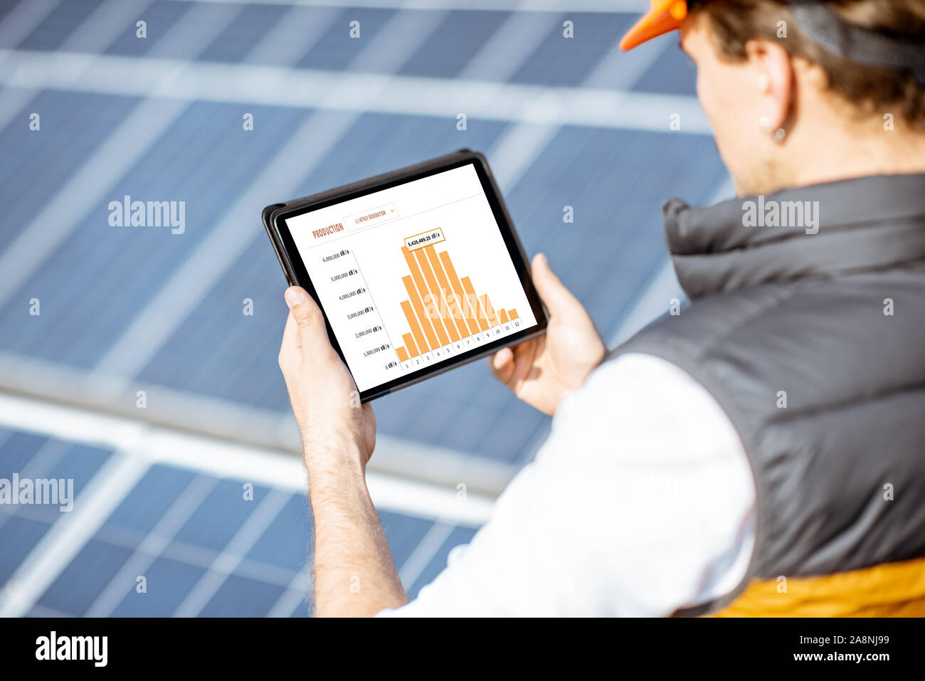 L'uomo esaminando genaration della centrale solare, tenendo tavoletta digitale con un grafico della produzione di elettricità. Concetto di monitoraggio online della stazione elettrica Foto Stock