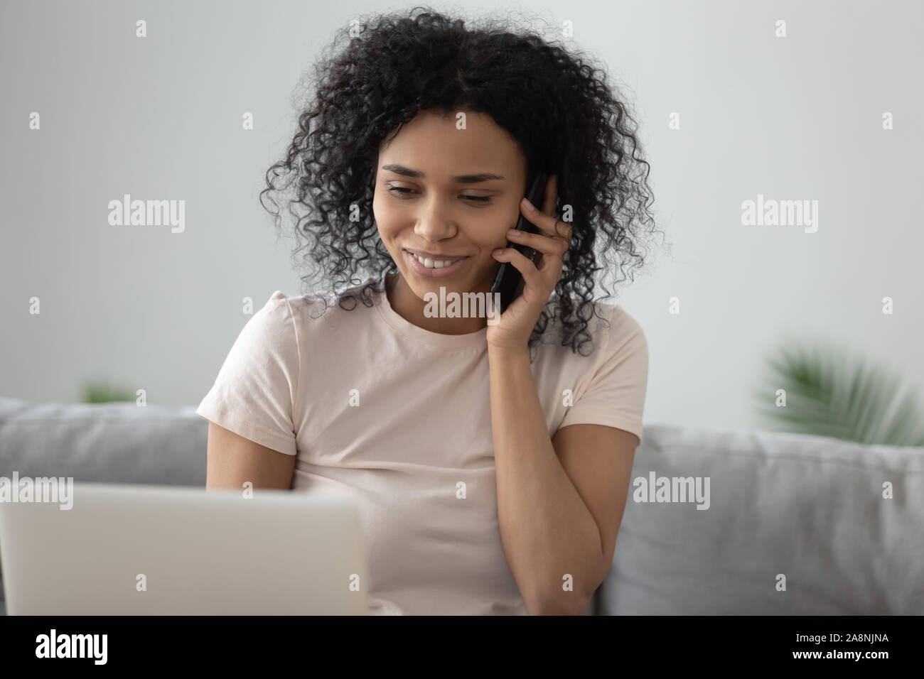 Sorridente americano africano donna parlando al cellulare a casa Foto Stock