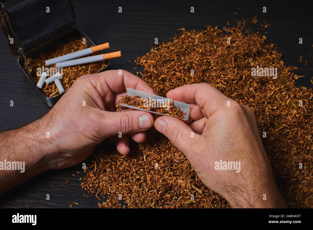 L'uomo fa una sigaretta, un rotolo di tabacco in carta tissue Foto Stock