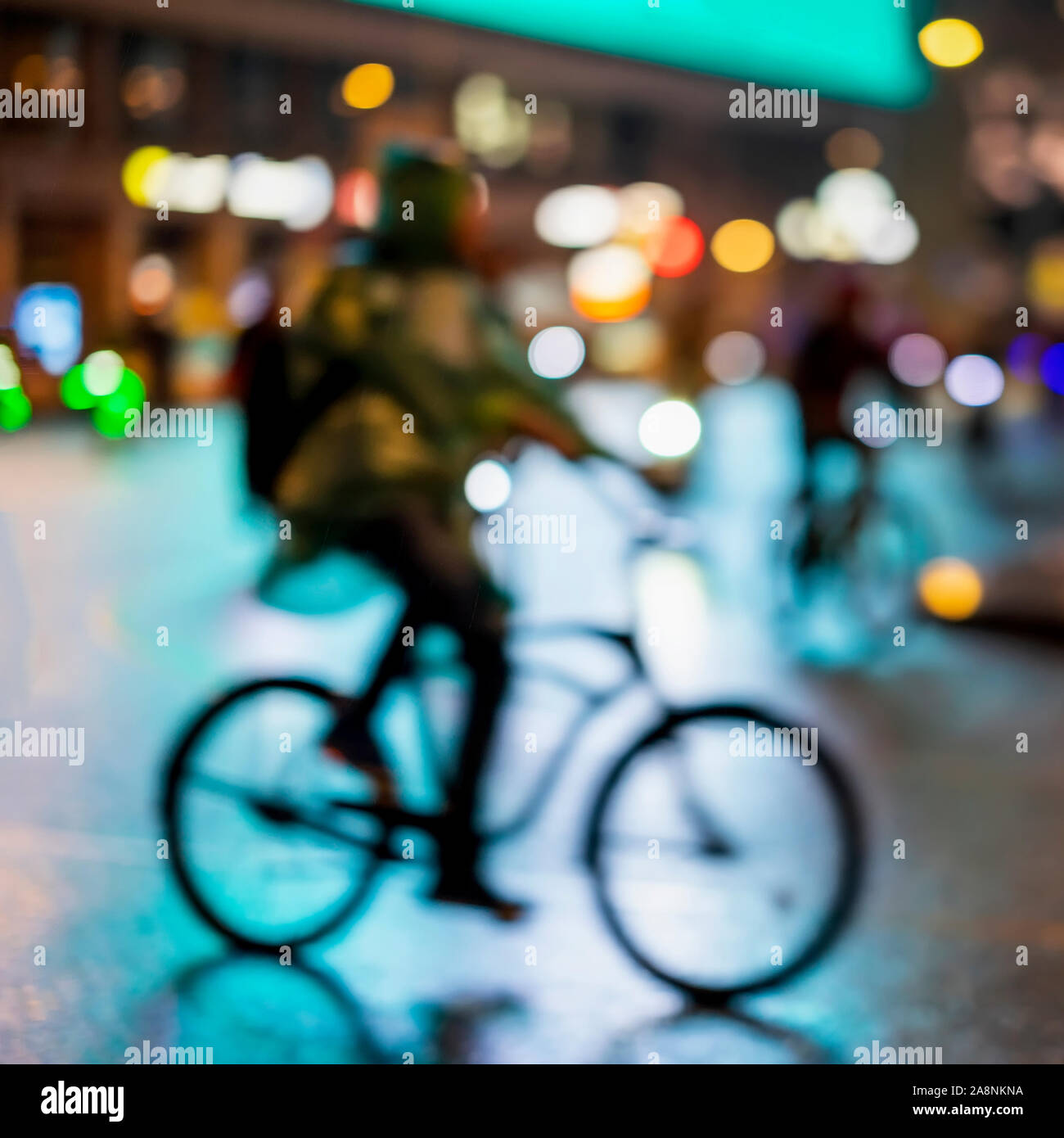 Abstract irriconoscibile silhouette uomo, equitazione biciclette, night city, illuminazione bokeh, motion blur. Uno stile di vita sano, attività di svago di concetto. Foto Stock