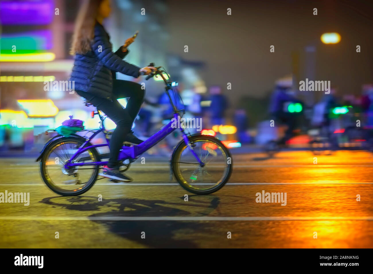 Abstract irriconoscibile ragazza Bicicletta Equitazione con lo smartphone, la città di notte, illuminazione bokeh, motion blur. Uno stile di vita sano, attività di svago di concetto. Foto Stock