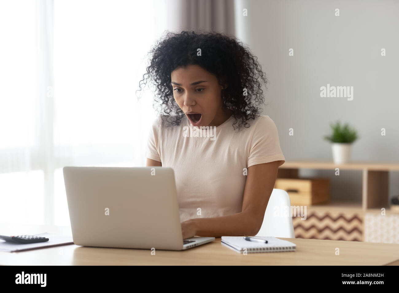 Scioccato americano africano donna con la bocca aperta utilizzando laptop Foto Stock