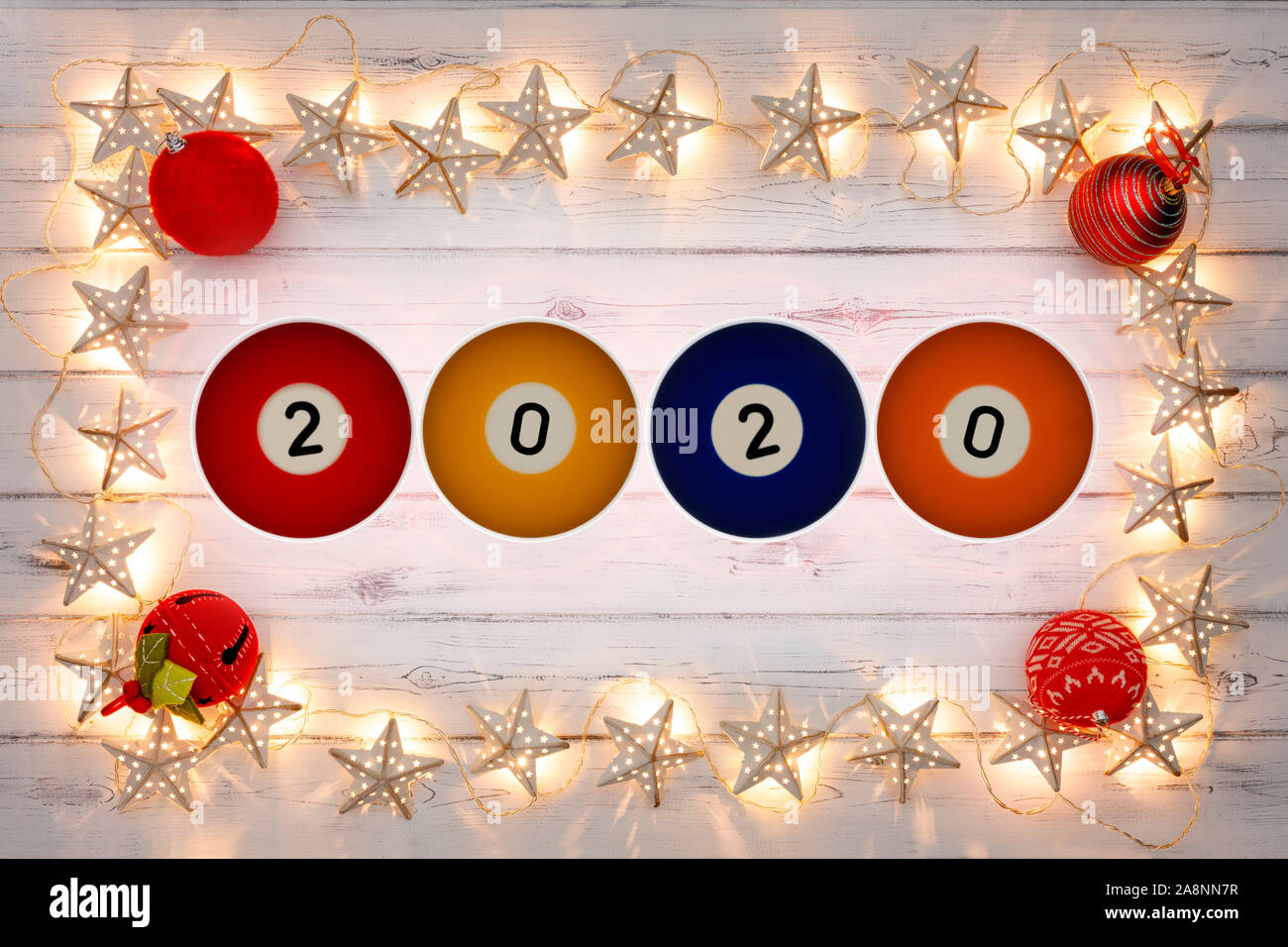 Una stringa di golden star le luci di Natale e baubles rosso, con 2020 piscina di palline in mezzo, su un destressed sfondo woodern Foto Stock