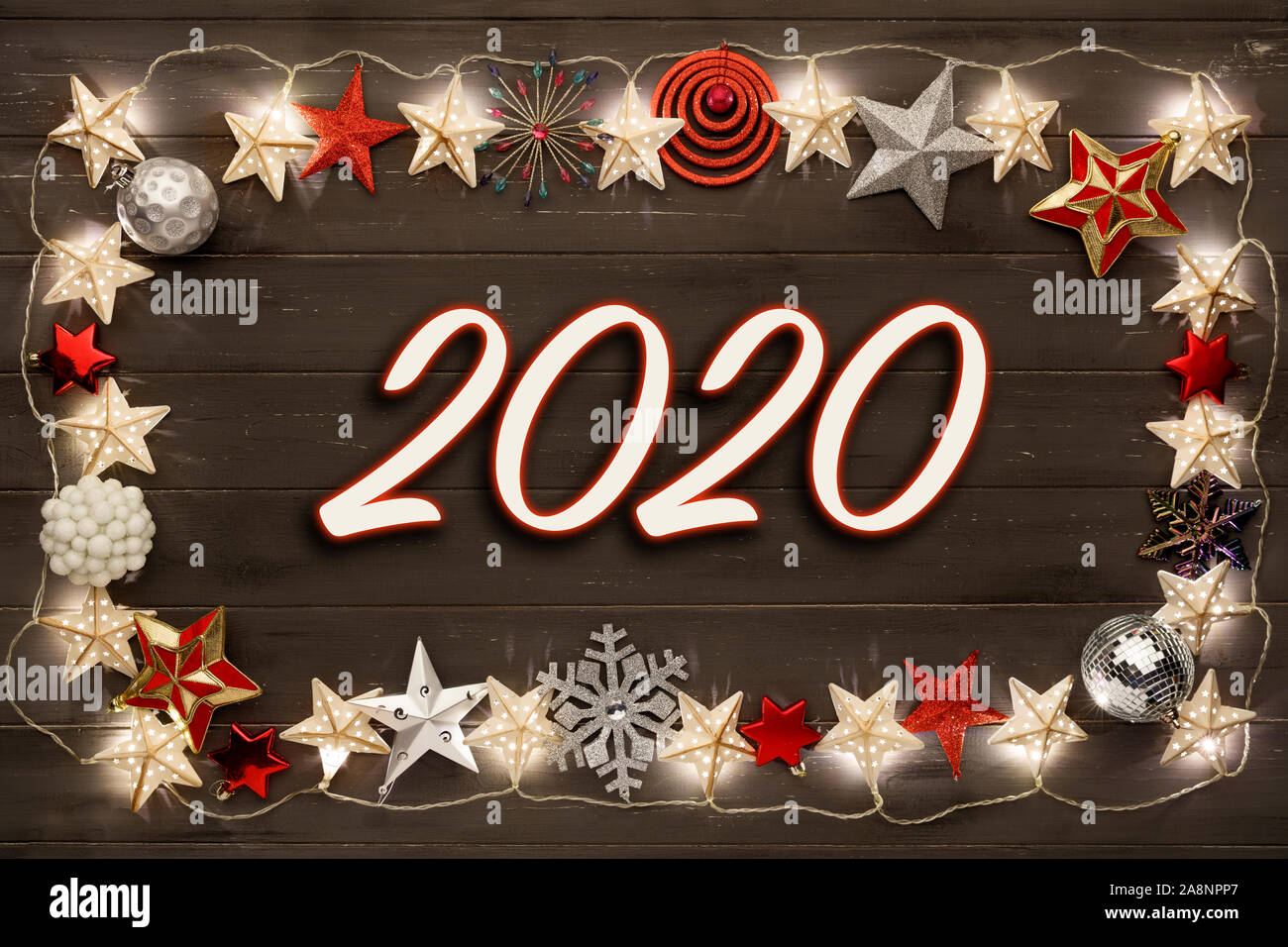 Una stringa di golden star le luci di Natale e star baubles, con 2020 al centro, su un destressed scuro dello sfondo woodern Foto Stock