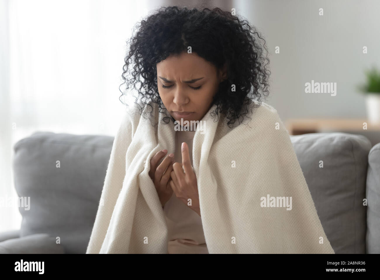 Infelici malati americano africano donna coperta con la calda coperta Foto Stock